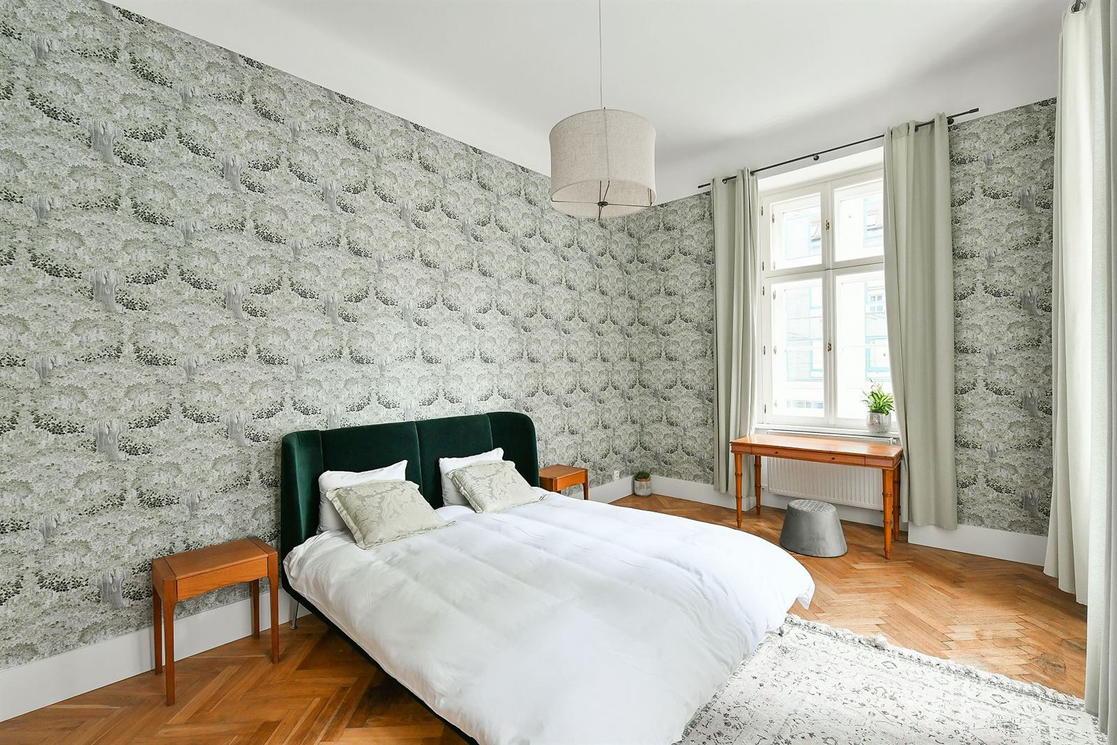 Bedroom with forest-green velvet bed, botanical wallpaper and herringbone parquet