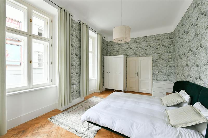 Tall bedroom windows with pale green curtains and city view