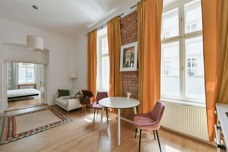 Round dining table with velvet chairs by tall windows and exposed brick